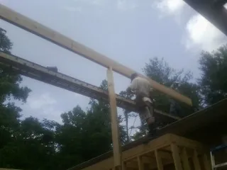 Carpenter setting a ridge beam over a new addition frame — Ice Dam Removal by Roofing Brothers in Old Monroe