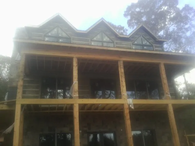 Dormers and porch framing on a large log home under construction — Roof Coating work by our crew in Old Monroe