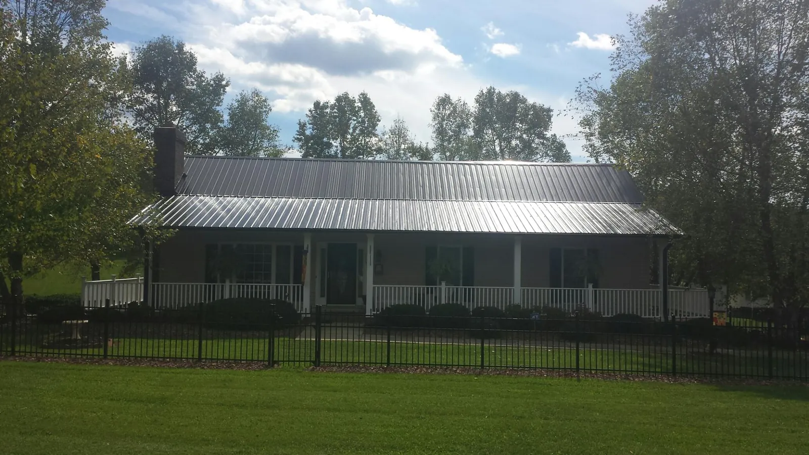 Gray metal roof on a brick ranch with a full width front porch — Gutter Guard Installation work by our crew in Old Monroe